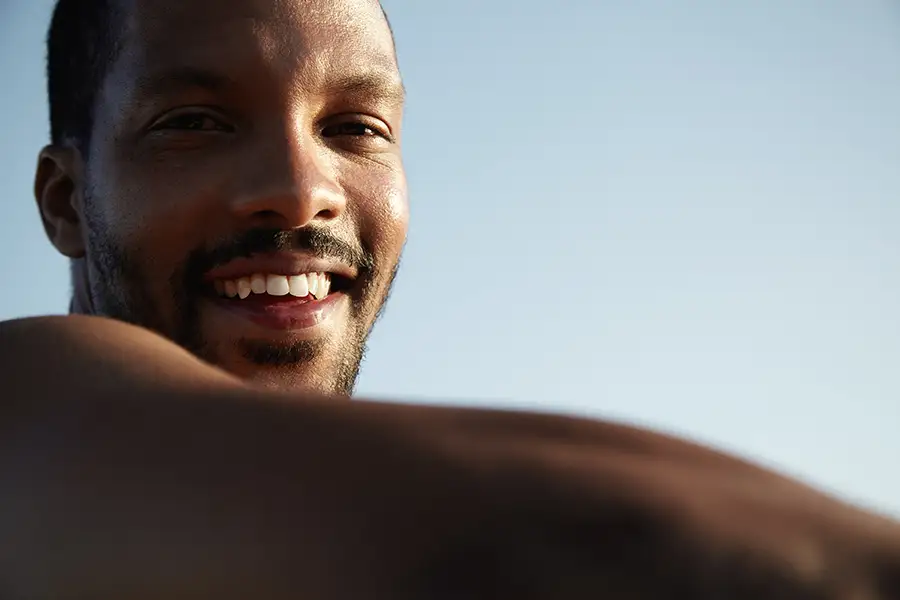 Well-groomed adult man smiling confidently in natural light, representing confidence and personalized intimate brightening care
